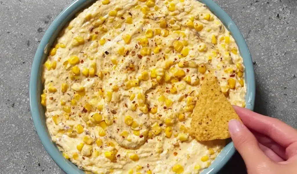 Creamy corn dip served in a bowl, garnished with herbs, perfect for parties