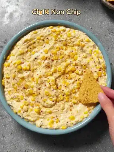 Creamy corn dip served in a bowl, garnished with herbs, perfect for parties