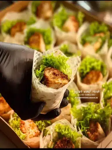 Plate of mini chicken wraps served with fresh vegetables and sauces