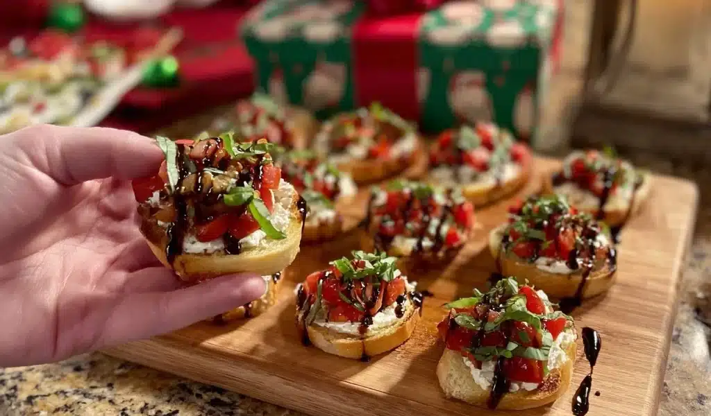 Ricotta crostini topped with roasted tomatoes on a wooden serving platter