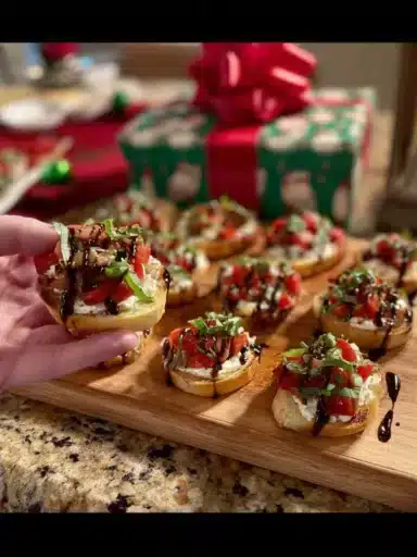Ricotta crostini topped with roasted tomatoes on a wooden serving platter